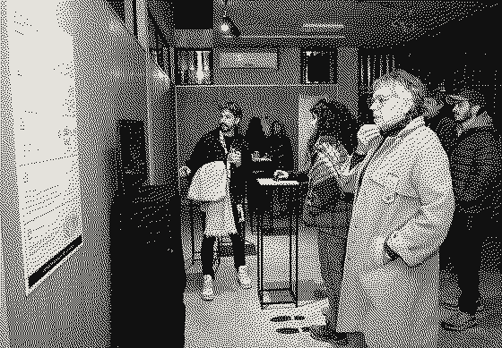 Visitantes escuchan junto al panel de sala; una persona usa el mouse sobre el pedestal
