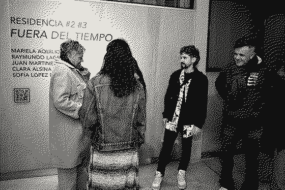Visitantes conversan frente al muro con el título RESIDENCIA #2 #3 FUERA DEL TIEMPO y los nombres de los artistas